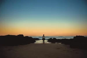 Woman walking alone on an empty beach — evoking solitude and introspection on Australia's Sunshine Coast