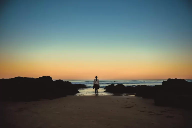 Woman walking alone on an empty beach — evoking solitude and introspection on Australia's Sunshine Coast